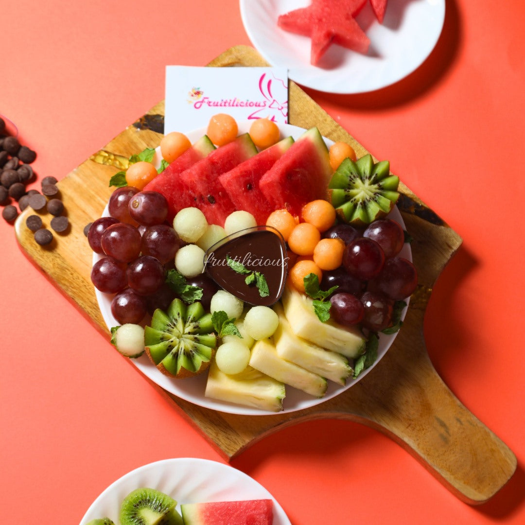 Fruit platter with a variety of fruits on a wooden board against a red background