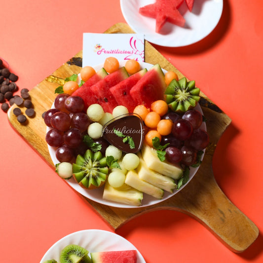 Fruit platter with a variety of fruits on a wooden board against a red background